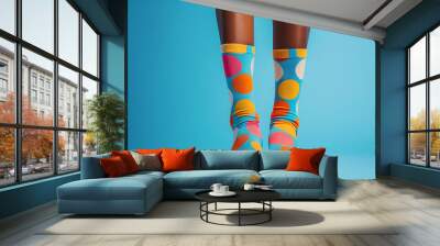 Person wearing colorful polka dot socks standing against a blue background, showcasing fun and playful fashion choices. Wall mural