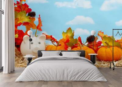 Fall savings with piggy bank and pumpkins and fall leaves on straw hay with sky Wall mural