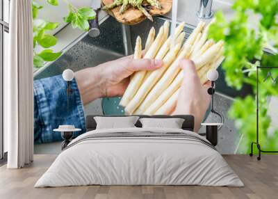 cropped shot of male hands in soil washing fresh asparagus in kitchen sink. Wall mural