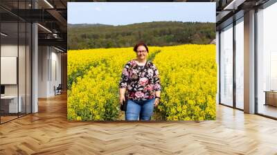 A woman is standing in a field of Blooming rapeseed	 Wall mural