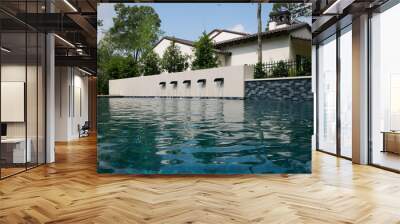 THE WOODLANDS, TEXAS - MAY 5th 2023: an outdoor pool and spa with water features on a hot sunny day. The blue water is sparkling and the Mediterranean style house is white with a terracotta roof. Wall mural