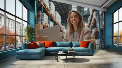 Smiling woman working on laptop in a busy warehouse during daytime Wall mural