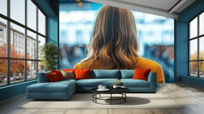 A woman giving a keynote speech at a startup conference in a sleek convention center attendees seated in rows focused and engaged vibrant corporate setting Wall mural