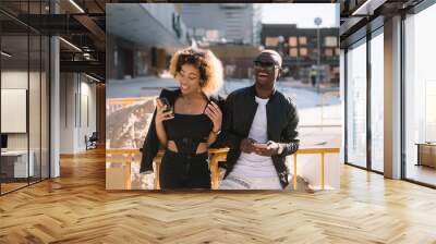 Afro couple using the smartphone on the street Wall mural