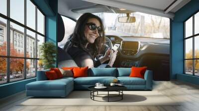 Beautiful young woman using her mobile phone in the car Wall mural