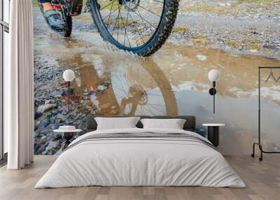 Man riding a mountain bike passing a puddle of water Wall mural