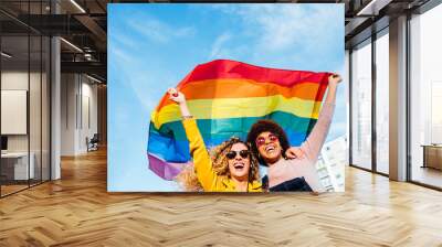 Two women friends hanging out in the city waving LGBT with pride flag Wall mural