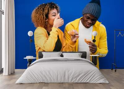 Young couple eating burger outdoors Wall mural