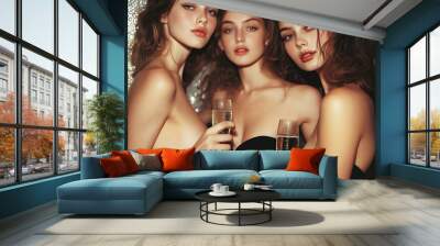 Three attractive young women holding champagne glasses, dressed in elegant evening attire, posing confidently at a glamorous party, with a focus on beauty and sophistication Wall mural