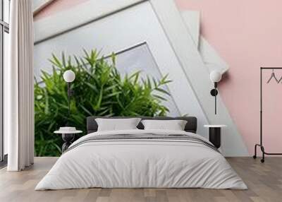 Flat lay with white frame and green plant on pink, minimalistic concept Wall mural