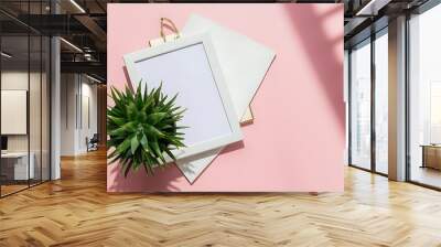 Flat lay with white frame and green plant on pink, minimalistic concept Wall mural