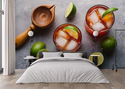 Flat lay with wooden squeezer, refreshing sour caipirinha cocktails with lime and ice on grey tabletop Wall mural