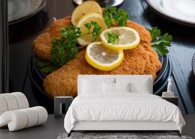 Homemade breaded wiener schnitzel served with parsley and lemon slices on dark wooden table Wall mural