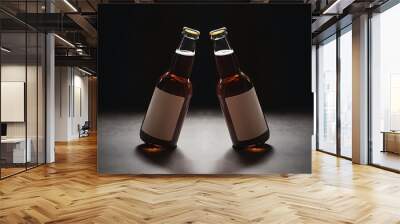 Low angle view of two glass bottles with beer and blank labels in row on dark background with back light Wall mural