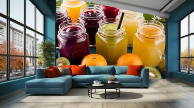 Organic fruit detox drinks in jars near oranges and kiwi isolated on blue Wall mural