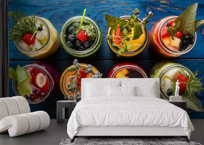 Top view of detox drinks in jars with fruits, vegetables, herbs, berries and greenery near fruit ingredients on wooden blue surface Wall mural