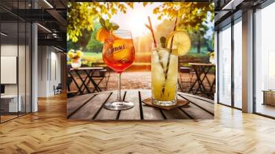 Two glasses with different summer refreshing cocktails on the table of a summer cafe in the park. Aperol syringe and lemonades. Wall mural