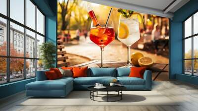 Two glasses with different summer refreshing cocktails on the table of a summer cafe in the park. Aperol syringe and lemonades. Wall mural