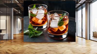 Two glasses with ice cubes and mint for alcohol drinks on table Wall mural