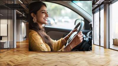 Pretty modern Indian woman is driving a car and smiling Wall mural