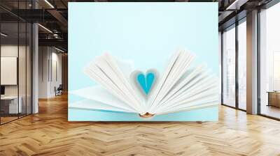 Pages of book curved into a heart shape on blue backdrop. Flat lay, empty space for text. Educational concept for school, bookshop, love for literature, Valentine's Day greeting Wall mural