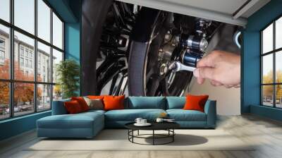 motorcycle mechanic use a wrench Adjust the belt pulley tension and drive belt on motorcycle working in garage .maintenance and repair motorcycle concept .selective focus Wall mural