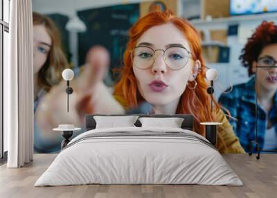 A photo of three women in a meeting room, one woman is taking a selfie with her phone while pointing at the camera and two other women sitting behind them looking on Wall mural