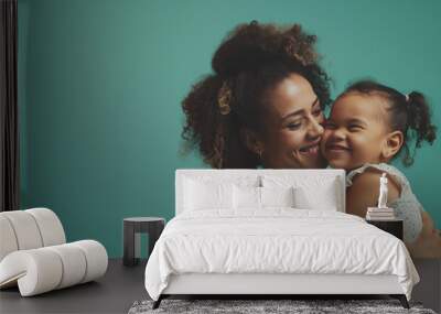 The camera focuses on Happy mother having fun with her daughter on teal color background professional photography. Wall mural