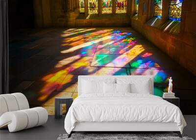 a stained glass window in an old cathedral, with the sunlight casting colorful reflections on the stone floor Wall mural