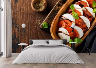 Caprese traditional italian salad in olive wooden bowl on old rustic background. Top view. Wall mural