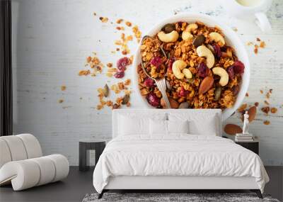 Homemade granola in glass jar with greek yogurt or milk and cashews, almonds, pumpkin with dried cranberry seeds in on white rustic wooden table background. Healthy energy breakfast or snack. Top view Wall mural