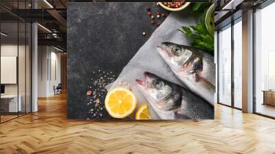 Sea Bass raw. Fresh sea fish bass with salt, pepper, parsley, olive oil and lemon on parchment paper on a dark concrete rustic background. Food cooking background. Top view, copy space. Wall mural