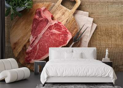 Thick Raw T-Bone Steak. Dry-aged Raw T-bone or porterhouse beef meat Steak on cutting boar with herbs and salt on dark background. Top view and copy space. Wall mural