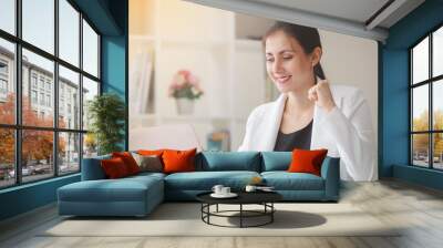 Successful business woman looking laptop with arms up Wall mural