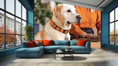 Labrador dog sits beside a person working on a laptop in a modern home office. Wall mural