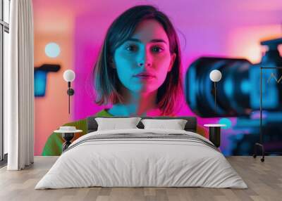 Young woman in colorful lighting, focused on camera, showcasing creativity and modern technology in photography. Wall mural