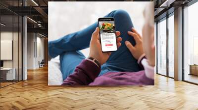 Man choosing a meal on food delivery app Wall mural