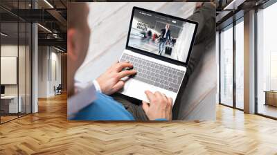 Man creating website for his business by using laptop computer Wall mural