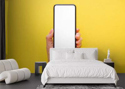 Mobile phone with empty screen in hand on yellow background Wall mural