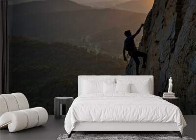 Silhouette of a climber on a steep cliff at sunset. Wall mural