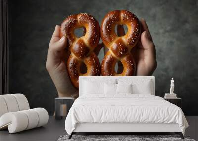 Two pretzels held by hands, symbolizing German cuisine. Wall mural