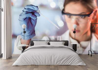 Life scientists researching in laboratory. Focused female life science professional pipetting solution into the glass cuvette. Lens focus on pipette. Healthcare and biotechnology concept. Wall mural