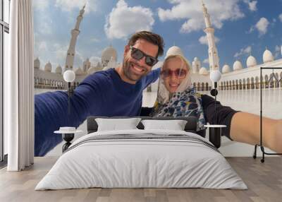 Tourist couple taking selfie in the courtyard of famous Sheikh Zayed Grand Mosque in Abu Dhabi, United Arab Emirates. Wall mural