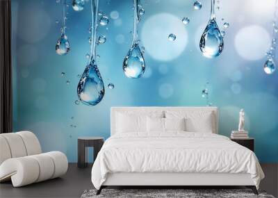 Glistening water droplets hang delicately against a soft blue background, capturing the essence of freshness and tranquility in nature. Wall mural