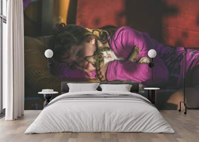 child and cat lying together in bed Wall mural