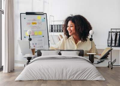 A woman is sitting at a desk with a laptop and a book Wall mural