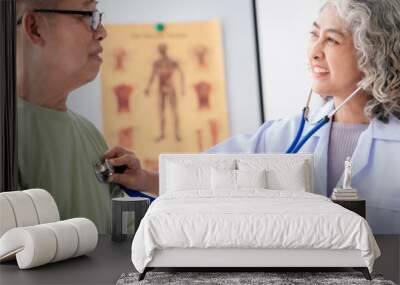 Female doctor using stethoscope to listening heart rate of senio Wall mural