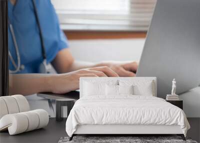 Veterinarian woman in blue uniform is using laptop to searching pet information and typing treatment Wall mural