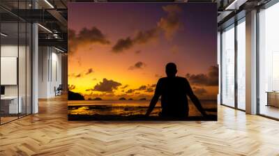 A guy silhouette enjoys a beautiful beautiful sunset on a tropical beach. Fiery sunset on the ocean Wall mural