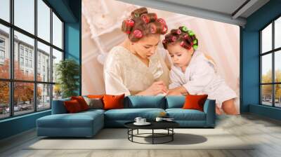 Adorable little girl with her mother in curlers paint their fingernails. Copies mom's behavior. Mom teaches her daughter to take care of herself. Beauty day Wall mural